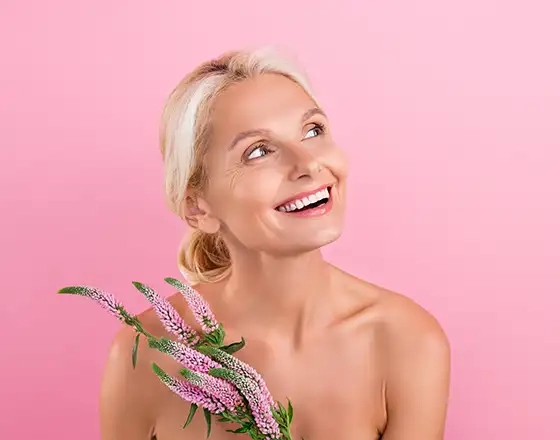 woman holding flowers and smiling and looking upwards to the side