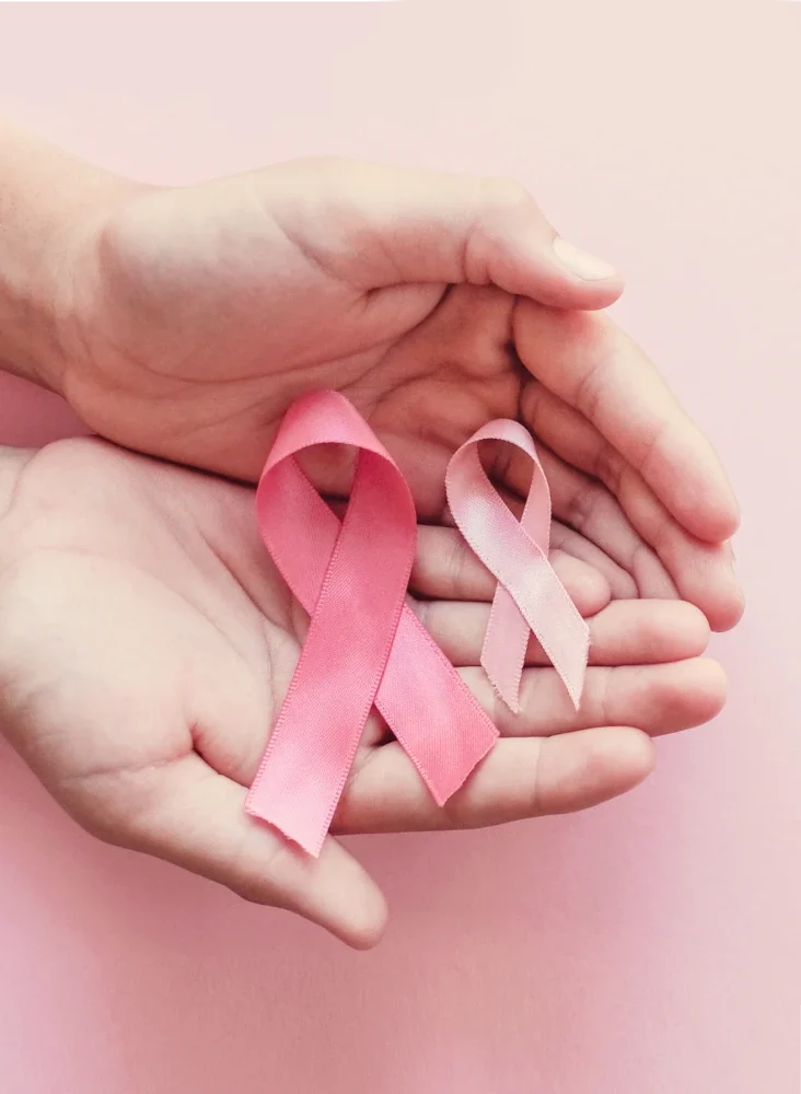 hands holding pink ribbon representing breast cancer awareness
