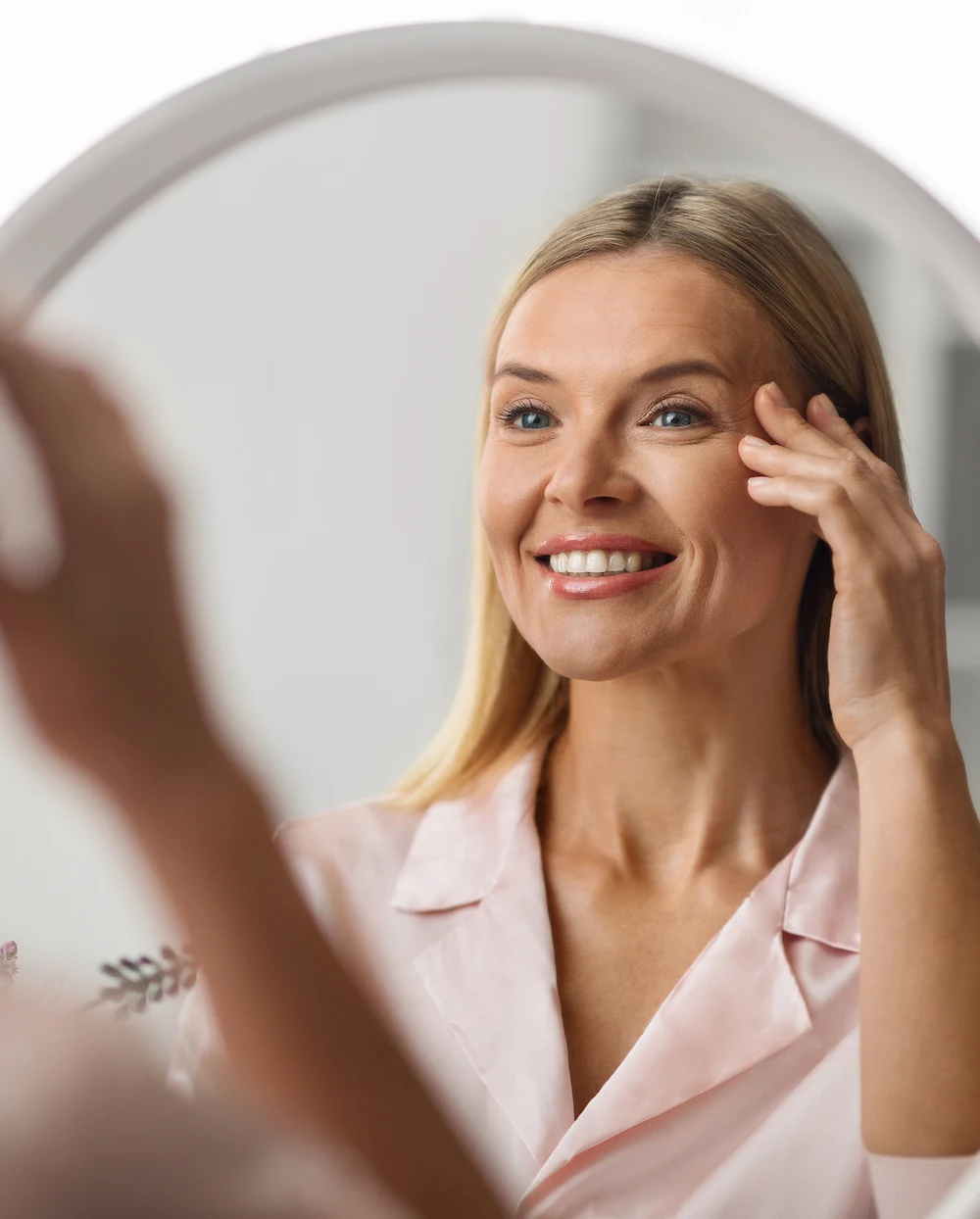 mature woman looking in the mirror at her beautiful blepharoplasty results